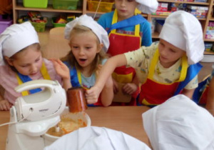 Chłopiec dodaje startą marchew do ciasta. Pozostałe dzieci po wyraźnym wrażeniem.